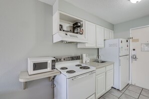 A compact kitchen with white appliances, including a microwave, stove, and refrigerator. - Beachfront Bliss & Ocean Views: Myrtle Beach Gem (Myrtle Beach)