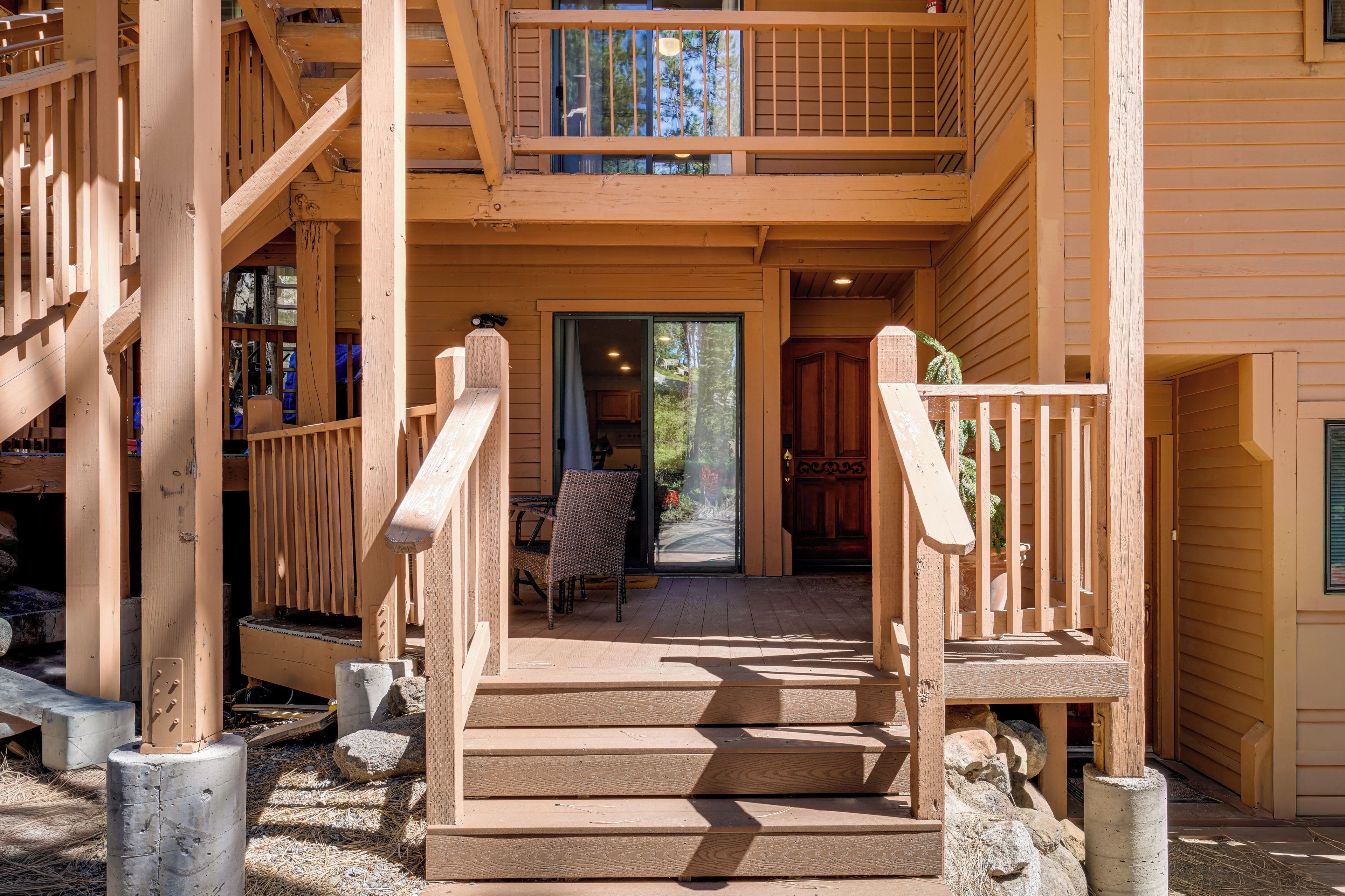 A wooden staircase leading to a covered porch with a dining table and chairs.