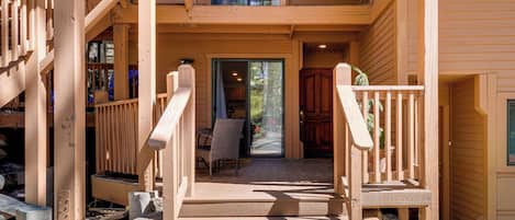 A wooden staircase leading to a covered porch with a dining table and chairs.