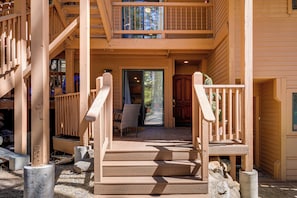Eine Holztreppe führt zu einer Veranda mit einem Esstisch und Stühlen.