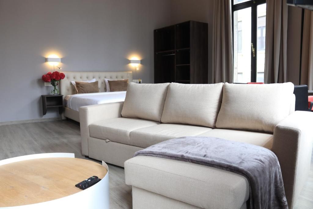 Una habitación de hotel con cama, sofá, mesa de centro y armario.
