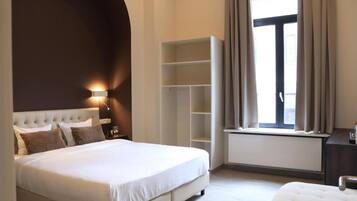 Een slaapkamer met een groot bed, een kledingkast, een nachtkastje en een raam met gordijnen.