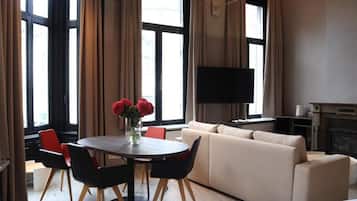 Een moderne woonkamer met een bank, een eettafel met stoelen, een wandgemonteerde flatscreen-tv en een open haard.