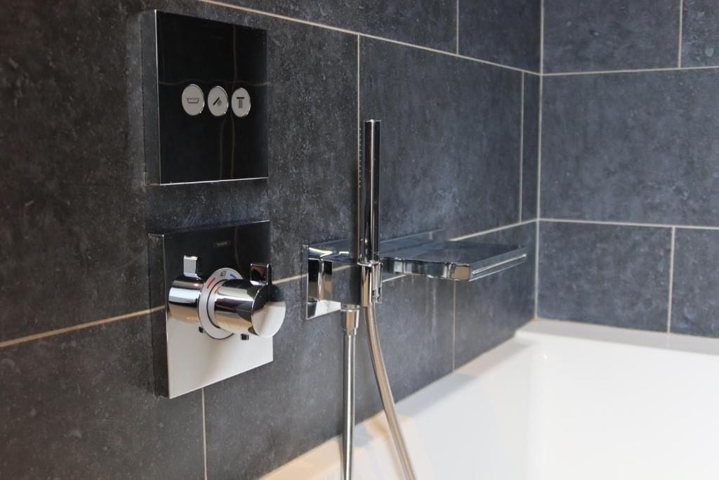 Une salle de bain moderne avec une douche intégrée, un robinet chromé et une étagère contenant des articles de toilette.