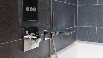 Une salle de bain moderne avec une douche intégrée, un robinet chromé et une étagère contenant des articles de toilette.