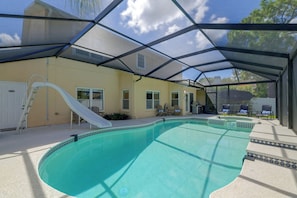 A covered outdoor swimming pool with a slide, a ladder, and lounge chairs. - Private Outdoor Oasis! Palm Harbor Family Escape (Palm Harbor)