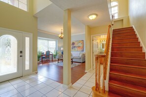 A spacious living area with a wooden staircase, a dining area, and a view of the outside. - Private Outdoor Oasis! Palm Harbor Family Escape (Palm Harbor)