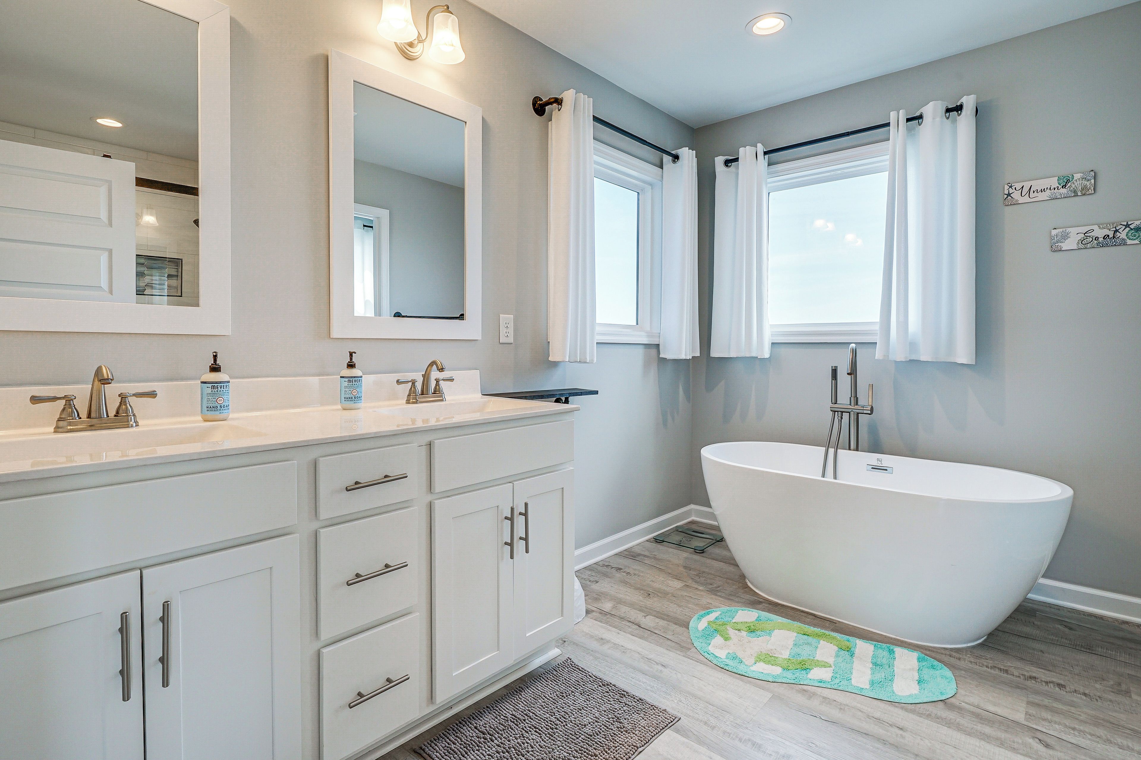 A modern bathroom with a freestanding bathtub, a double vanity with two sinks, and a large mirror above the vanity.