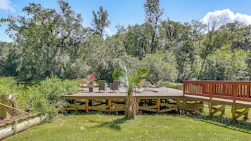 A wooden deck with outdoor seating and a view of a lake surrounded by trees.