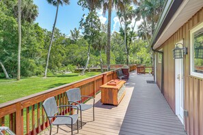 A wooden deck with outdoor seating and a view of a lush, green landscape. - Riverfront Apopka Studio Near Wekiwa Springs! (Apopka)