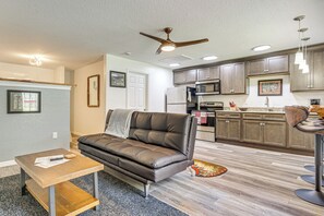 A modern living room with a leather sofa, a dining table, and a kitchen area with wooden cabinets and appliances. - Riverfront Apopka Studio Near Wekiwa Springs! (Apopka)