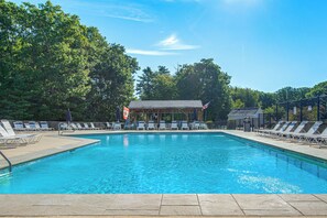 Una piscina con sillones de descanso y un pabellón.