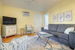 A living room with a television, a sofa, a coffee table, and a chair. - Charming Coastal Getaway in Wells, Maine (Wells)