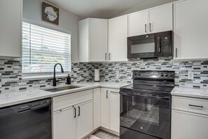 A modern kitchen with white cabinets, a black microwave, and a stainless steel oven.