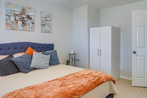 A bedroom with a bed, a wardrobe, and two paintings on the wall.
