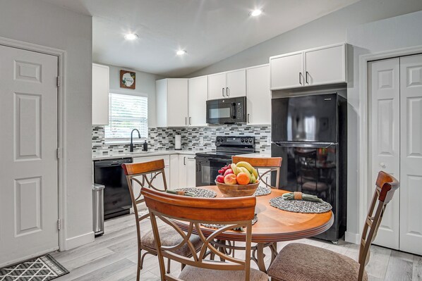 A modern kitchen with white cabinets, a black refrigerator, and a dining table with chairs. - Suburban Snowbird Escape 22 Mi to Dtwn Fort Myers (Fort Myers)