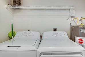Two white front-loading washing machines with control panels, a green mop, and a stop sign on the wall.