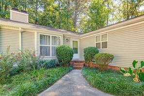 A residential house with a front yard, a pathway leading to the front door, and a small garden area with various plants and shrubs. - Raleigh Townhome w/ Deck: Near Shops & Dining (Raleigh)