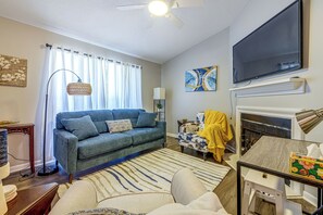 A living room with a sofa, a television, a fireplace, and a ceiling fan. - Raleigh Townhome w/ Deck: Near Shops & Dining (Raleigh)