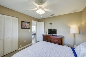 A bedroom with a bed, a dresser, a television, a ceiling fan, and a door leading to a balcony. - Heated Pool, Fishing Dock! Florida Escape on Canal (Port Charlotte)