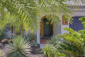 A house with a dark front door, surrounded by various plants and a small porch area. - Heated Pool, Fishing Dock! Florida Escape on Canal (Port Charlotte)