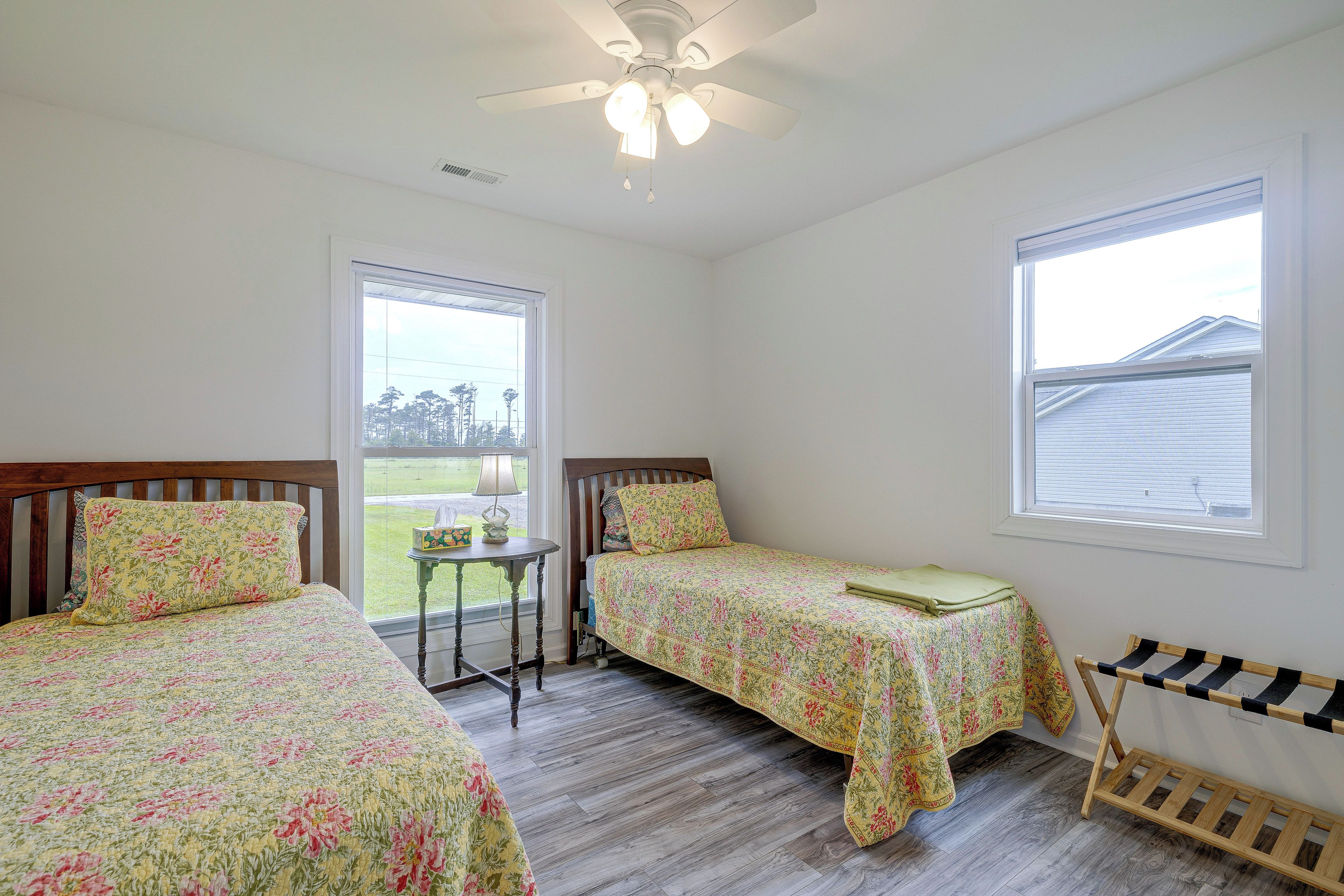 A bedroom with two beds, a ceiling fan, a window, and a view of the outdoors.