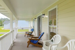 A covered porch with two wooden rocking chairs and a white plastic chair. - Beaufort Home Near Fishing & Historic Waterfront (Beaufort)