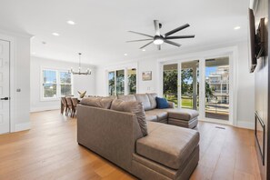 Ein geräumiges Wohnzimmer mit Ecksofa, Deckenventilator und einem Essbereich mit Stühlen und Tisch.