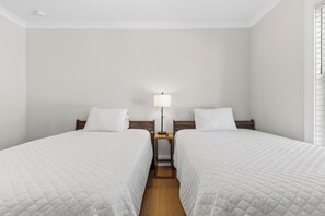 A hotel room with two beds, a nightstand with a lamp, and a window with blinds. - 🌊Ocean Blvd Retreat at the Beach: Newly Built 5Br🏖️ (Carolina Beach)