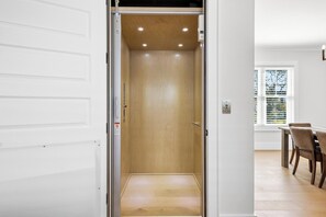 An interior view of a room with a wooden floor, a white door, and a window with blinds. - 🌊Ocean Blvd Retreat at the Beach: Newly Built 5Br🏖️ (Carolina Beach)