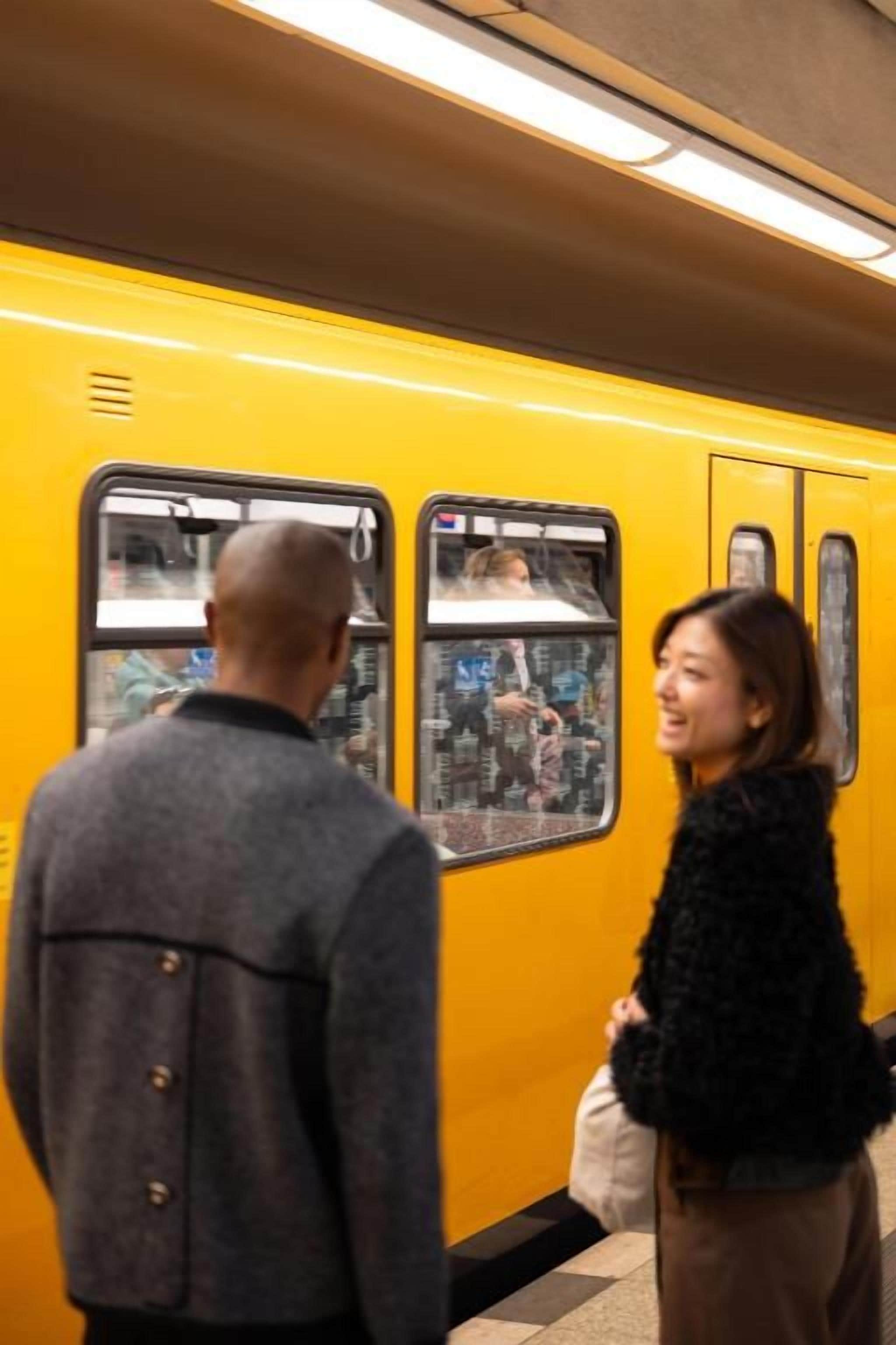 Een gele trein met een man en een vrouw die ervoor staan.