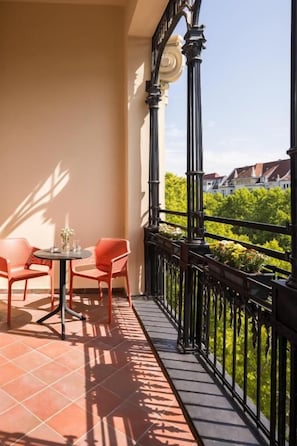A balcony with a table and chairs, a railing, and a view of greenery and buildings. - FU Life Berlin Kudamm (Berlin)