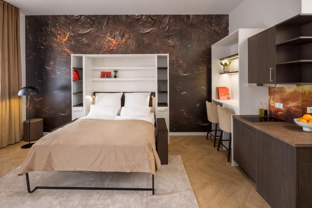 Un dormitorio moderno con cama, mesitas de noche, armario y una pequeña cocina.