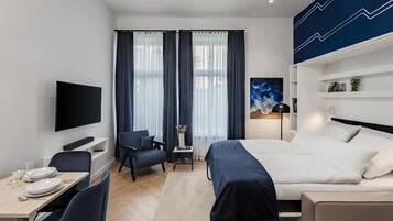 Une chambre d’hôtel moderne équipée d’un lit, d’un bureau avec une chaise, d’une télévision et d’une fenêtre avec des rideaux.