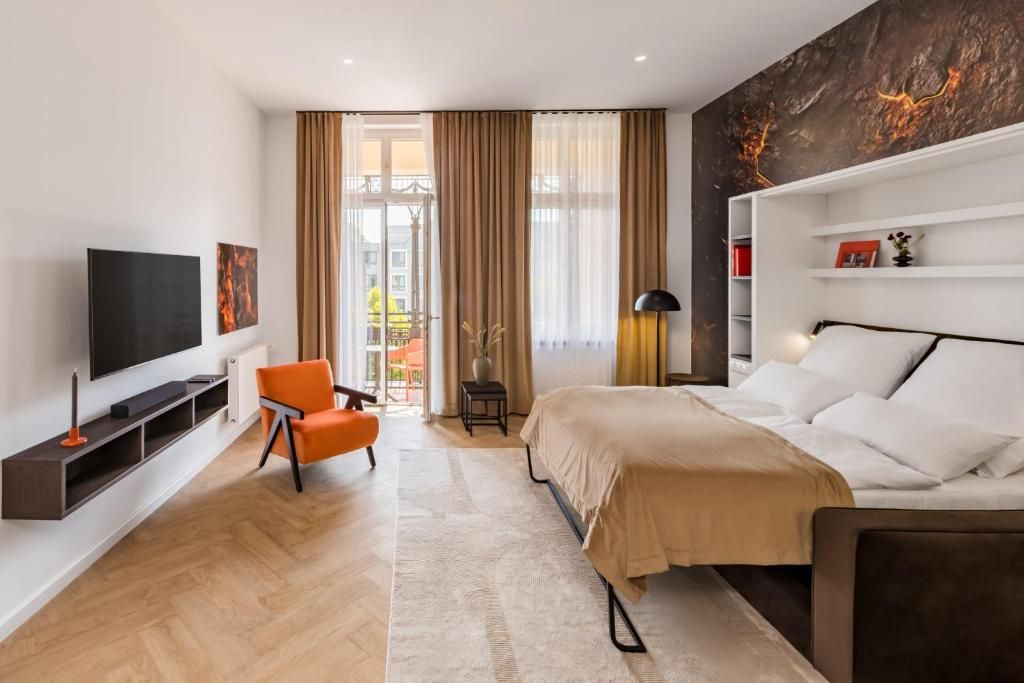 Habitación de hotel moderna con cama, televisión, zona de estar y vistas al exterior.