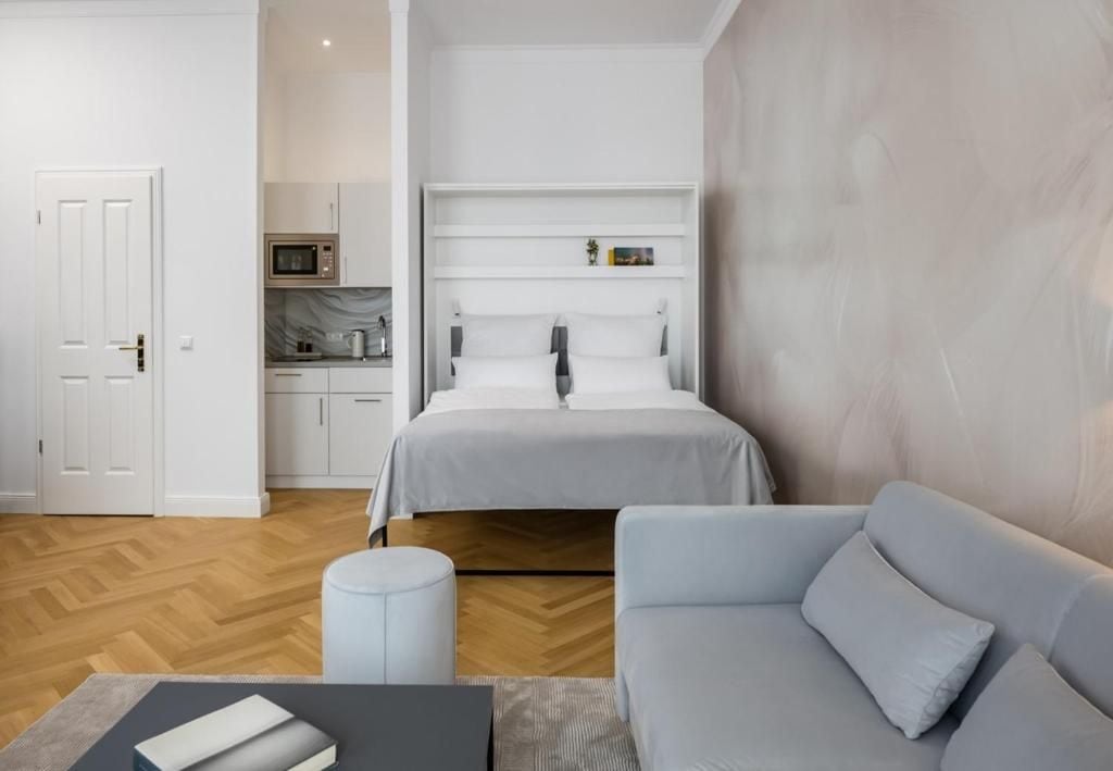 Ein modernes Schlafzimmer mit Bett, Sofa, kleinem Tisch und einer Küchenzeile.