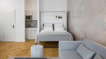 Ein modernes Schlafzimmer mit Bett, Sofa, kleinem Tisch und einer Küchenzeile.