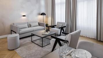 Ein modernes Wohnzimmer mit Sofa, Sesseln, einem Couchtisch und einer Essecke für zwei Personen.