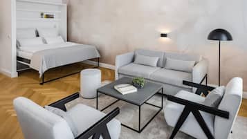 Un dormitorio moderno con una cama, un sofá gris, una mesita de centro y una lámpara de pie.
