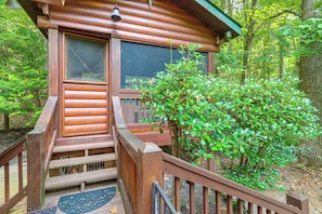 A wooden cabin with a porch, a window, and a door. - Pet-friendly Cozy Cabin Retreat Hot Tub & Trails (Cherry Log)