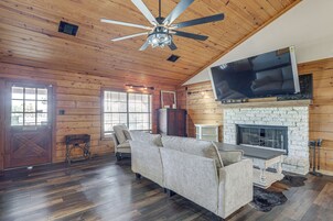 Amplia sala de estar con ventilador de techo, chimenea, televisor grande y un sofá acogedor.