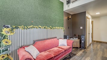 Une pièce avec un canapé rouge, un mur à rayures verticales et un mur vert à texture.