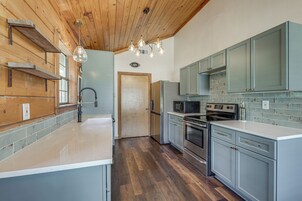 Una cocina con vigas de madera en el techo, una isla central, electrodomésticos de acero inoxidable y armarios de color azul claro.