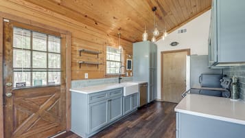 Une cuisine avec un plafond en bois, une grande fenêtre et une porte.
