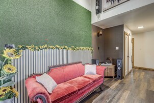 Una habitación con un sofá rojo, una pared con rayas verticales y una pared verde con textura.