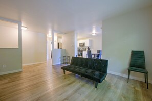 Una sala de estar moderna con un sofá, una zona de comedor con sillas y una cocina al fondo.