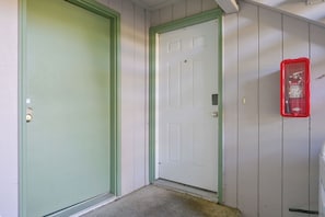 A hallway with two doors, one green and one white, and a red fire extinguisher mounted on the wall. - 3 Mi to Olympia! Apt w/ Shared Laundry (Lacey)