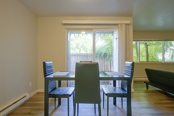 A dining area with a table and four chairs, a bench, and a sliding glass door leading to a deck. - 3 Mi to Olympia! Apt w/ Shared Laundry (Lacey)
