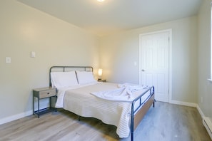 Un dormitorio con cama, mesita de noche, lámpara y puerta.