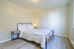 Un dormitorio con cama, mesita de noche, lámpara y puerta.